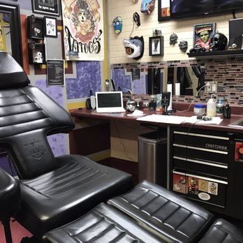 Body Ritual tattoo station with a black tattoo chair, artwork, and equipment